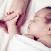 Newborn baby and his father’s hand – care and safety concept