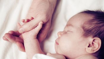 Newborn baby and his father’s hand – care and safety concept