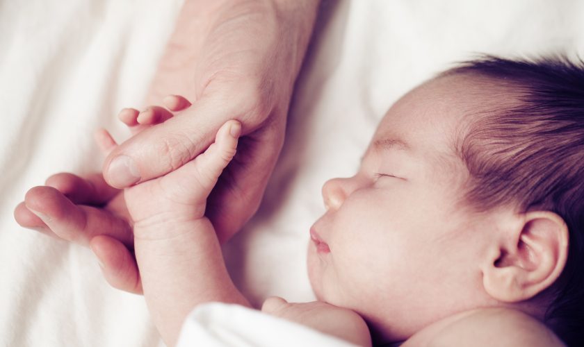 Newborn baby and his father’s hand – care and safety concept