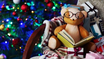 Teddy bear with book and gift boxes in rocking chair